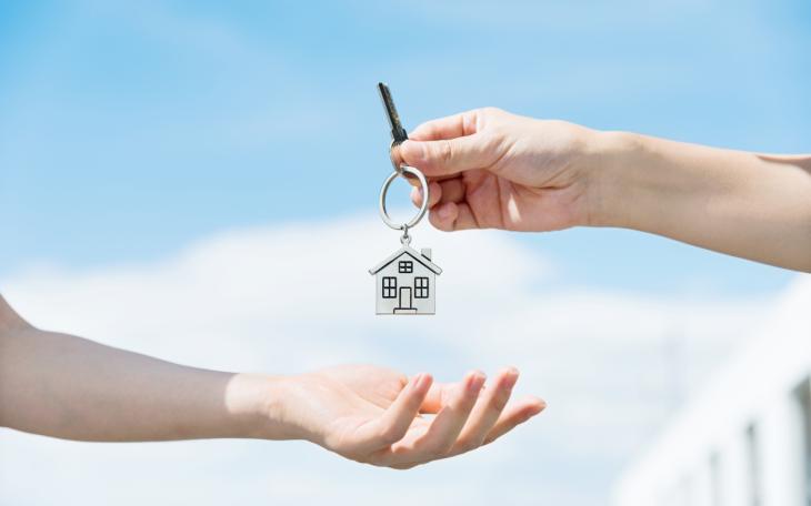 someone handing over a key with the blue sky in the background